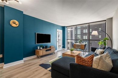 Open-concept living area with floor-to-ceiling windows, rich accent wall, and seamless flow into the kitchen and dining spaces.