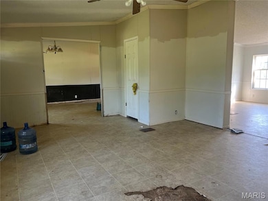 Tiled empty room with crown molding, a wainscoted wall, a ceiling fan, and a textured ceiling