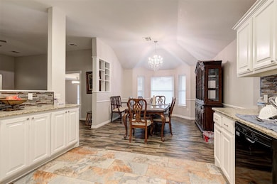 Dining area with a chandelier, light stone finish flooring, and vaulted ceiling