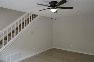 Empty room featuring stairs, wood finished floors, ceiling fan, and a textured ceiling