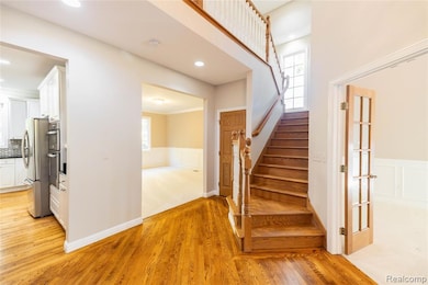 Stairs with wood finished floors, wainscoting, a decorative wall, recessed lighting, and ornamental molding