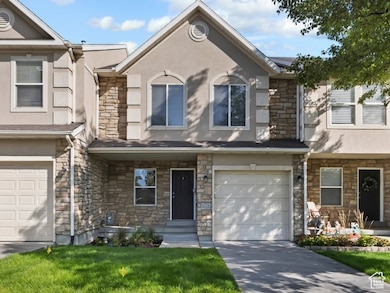 Traditional home featuring stone siding, stucco siding, driveway, and an attached garage