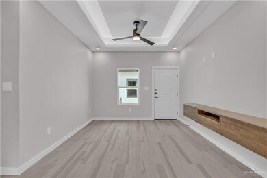 Empty room with a raised ceiling, light wood-style flooring, a ceiling fan, and recessed lighting