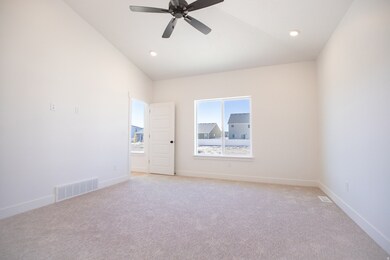Primary bedroom with vaulted ceiling and ceiling fan.