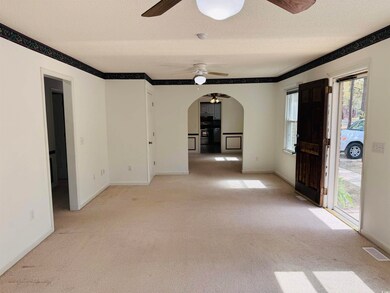 Spare room featuring a ceiling fan, arched walkways, a textured ceiling, and light carpet