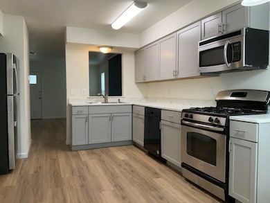 Kitchen featuring gray cabinetry, appliances with stainless steel finishes, and light countertops.