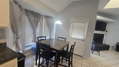 Dining space with light tile patterned floors, vaulted ceiling, and a fireplace