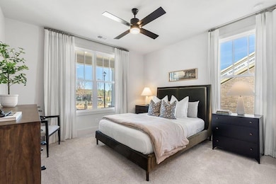 Bedroom featuring a ceiling fan, multiple windows, light colored carpet, and visible vents