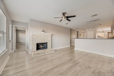 Unfurnished living room featuring light wood finished floors, a stone fireplace, a ceiling fan, and rail lighting