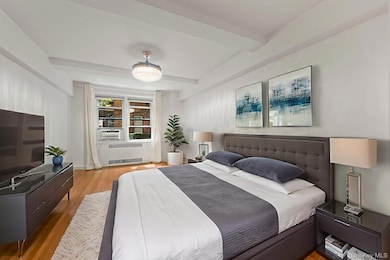 Primary Bedroom with beamed ceiling, light wood-style flooring, and radiator