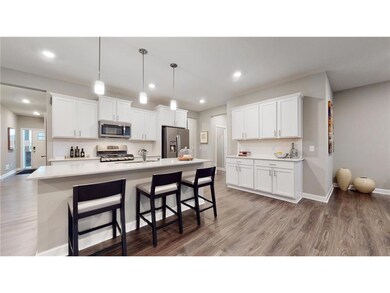 This dream kitchen features plenty of cabinet space, an oversized center island, quartz countertops, tile backsplash, walk-in pantry and the popular slate finish appliances! Photo of model home, colors and finishes will vary.