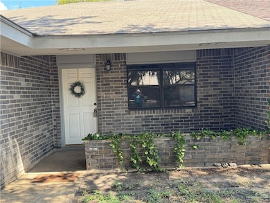 Doorway to property with brick siding and a shingled roof