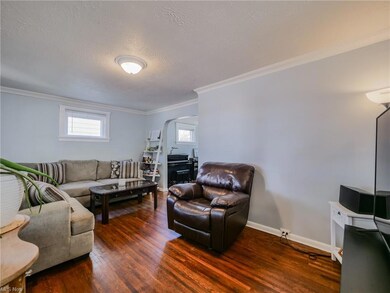 Hardwood floored living room with a healthy amount of sunlight, ornamental molding, and a textured ceiling