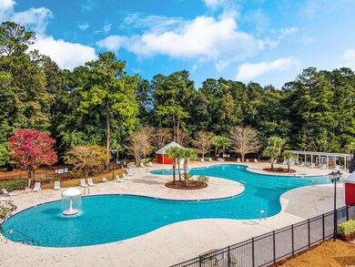 Community pool featuring a patio area and view of wooded area