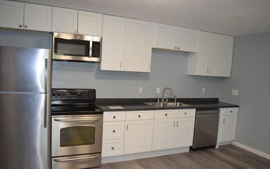 Kitchen featuring stainless steel appliances, a sink, dark wood-style flooring, and white cabinets