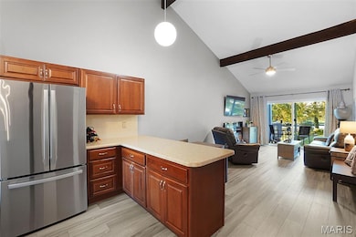 Kitchen featuring freestanding refrigerator, light countertops, beamed ceiling, high vaulted ceiling, and a peninsula