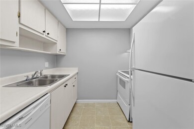 Kitchen with baseboards, white appliances, light c