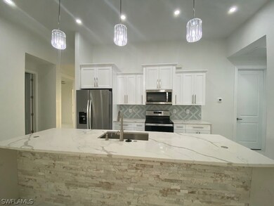 Kitchen featuring refrigerator, decorative light fixtures, stove, and light stone countertops