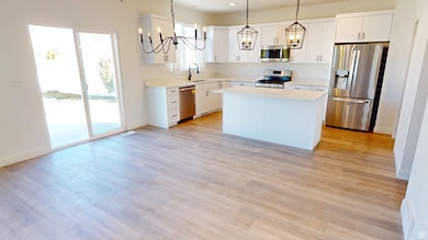 Kitchen featuring appliances with stainless steel finishes, hanging light fixtures, a center island, white cabinetry, and a chandelier