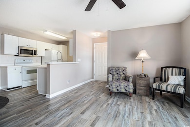 Living area with newly installed LVP flooring, a ceiling fan, baseboards, and a textured ceiling