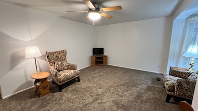 Living area featuring carpet and a ceiling fan