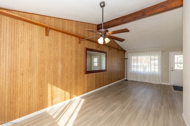 Empty room featuring wood finished floors, wooden walls, and a ceiling fan