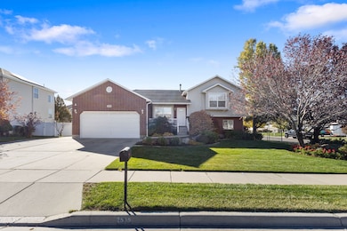 Tri-level home featuring driveway, brick siding, and a garage