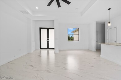 Spare room with french doors, light marble finish floors, a tray ceiling, and recessed lighting