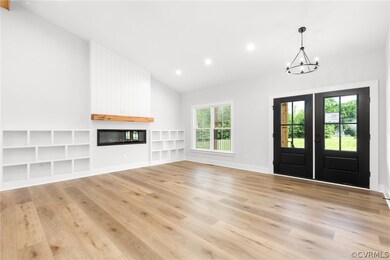 Foyer with a healthy amount of sunlight, light wood-type flooring, vaulted ceiling, and a chandelier