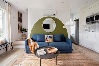Living room with an AC wall unit, light wood-style flooring, and recessed lighting