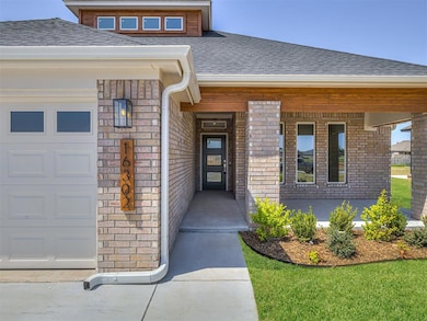 View of exterior entry featuring brick siding, a shingled roof, and a garage