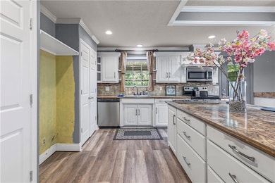 Kitchen with white cabinetry, crown molding, dark wood finished floors, a textured ceiling, and stainless steel appliances