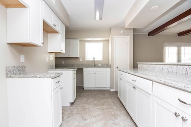 Kitchen with a sink, light stone counters, and healthy amount of natural light