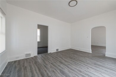 Empty room featuring arched walkways and wood finished floors