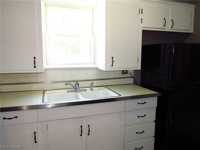 Kitchen with backsplash, black fridge, sink, and a wealth of natural light