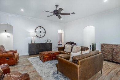 Living room with crown molding, ceiling fan, and l