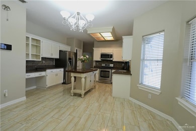 Kitchen featuring appliances with stainless steel finishes, tasteful backsplash, decorative light fixtures, and white cabinets