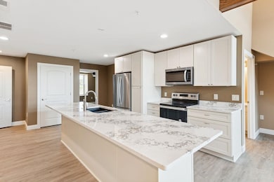 Kitchen featuring a center island with sink, light wood-type flooring, appliances with stainless steel finishes, and sink