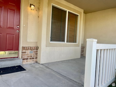 Doorway to property featuring stucco siding, brick siding, and a porch