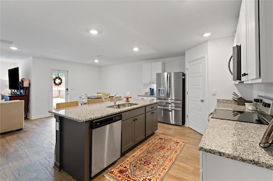 Kitchen with white cabinets, sink, light wood-type