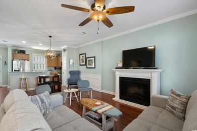 Living area with ceiling fan with notable chandelier, recessed lighting, a fireplace, crown molding, and dark wood-style floors
