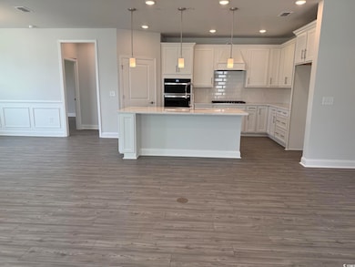 Kitchen with double oven, black gas cooktop, light countertops, dark wood-type flooring, and recessed lighting