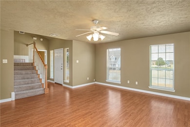 Unfurnished living room featuring stairs, light wood-style flooring, a textured ceiling, and ceiling fan