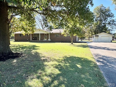 View of grassy yard with a garage, driveway, and an outdoor structure