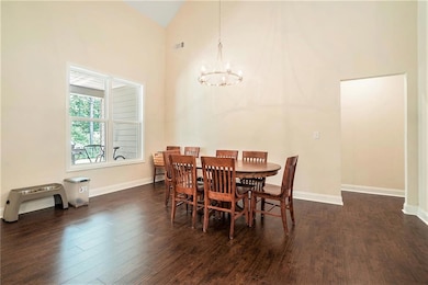 Dining space with a chandelier, high vaulted ceiling, wood finished floors, and baseboards