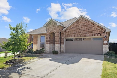 View of front of house with roof with shingles, brick siding, driveway, a garage, and stone siding