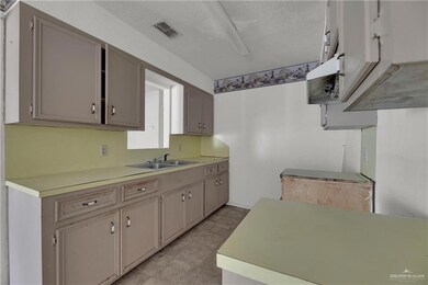 Kitchen with sink, light tile floors, and a textured ceiling