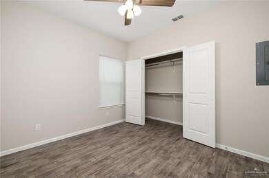 Unfurnished bedroom with electric panel, wood finished floors, a closet, baseboards, and ceiling fan