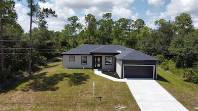 View of front facade with a garage, concrete driveway, a front lawn, and roof with shingles