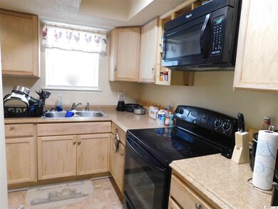 Kitchen featuring black appliances, light brown cabinetry, light countertops, and a sink